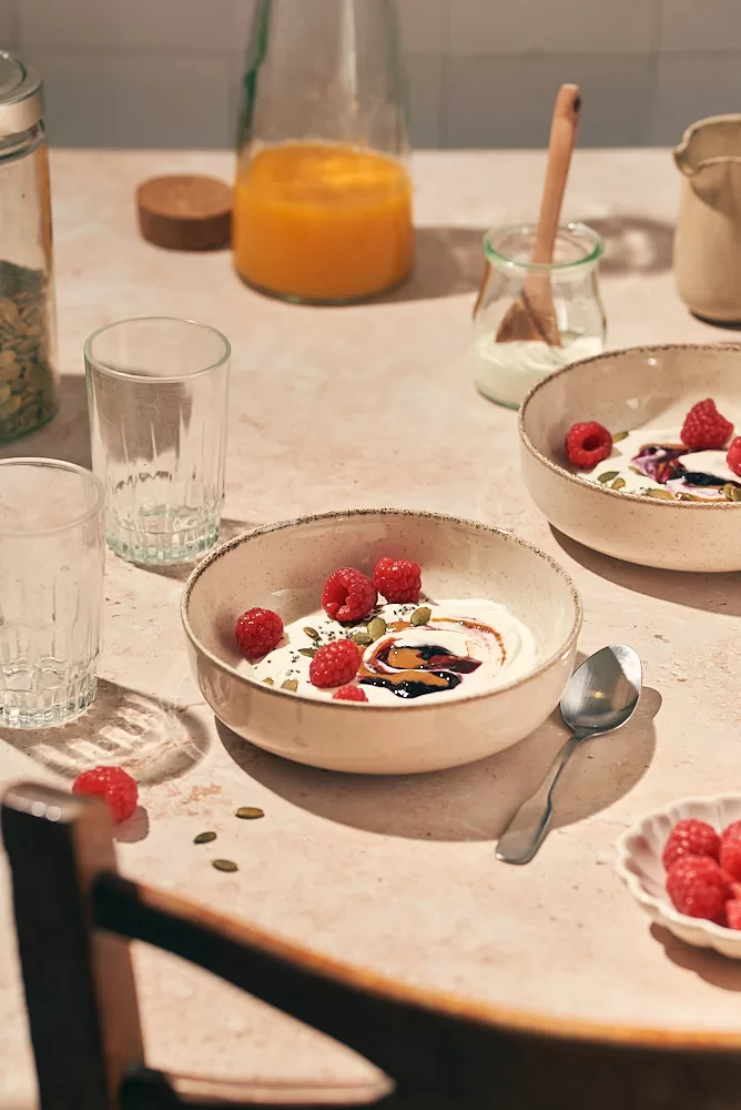 Food photography in Barcelona of sunny, bright and colorful breakfast scene with raspberries and yogurt