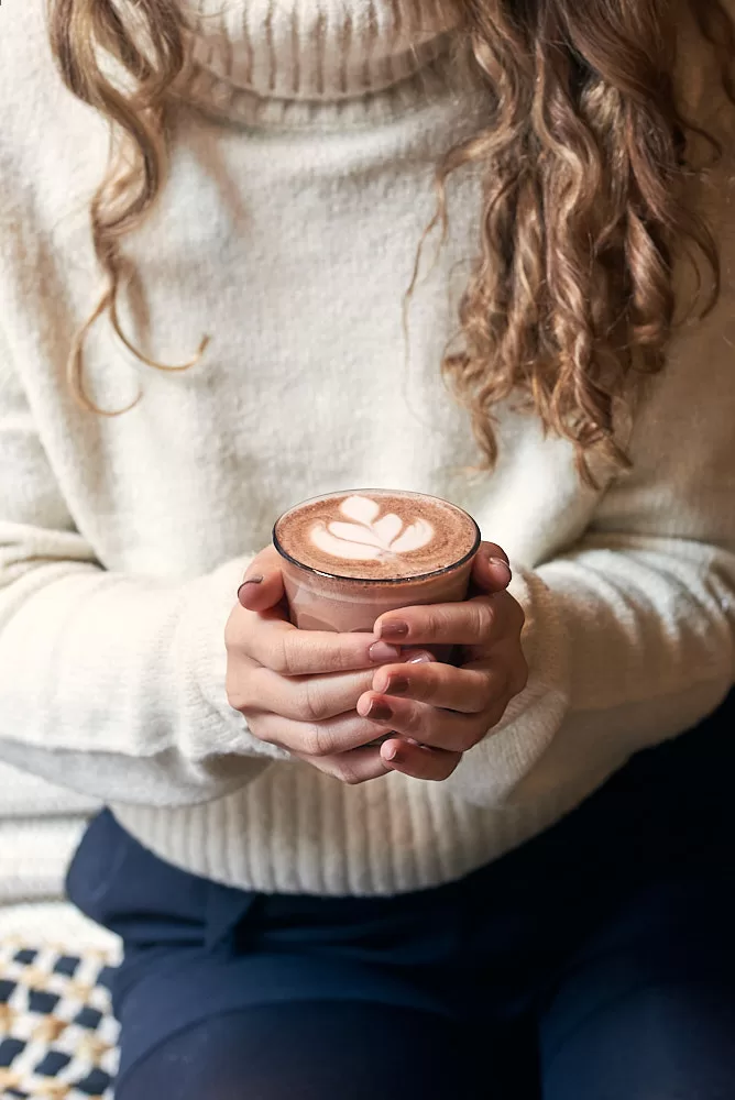 Beverage photography of girl holding a hot chocolate at Barcelona cafe